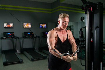 Athletic strong bodybuilder deals with a dumbbell in the gym