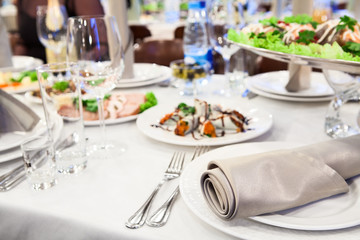 A celebratory table with cold dishes, white plates, cutlery and napkins