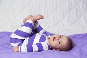 A cute 6 month old baby girl is laying holding her toes .