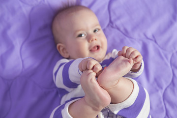 A cute 6 month old baby girl is laying holding her toes .