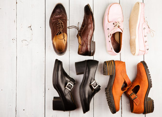 Set of different unisex shoes on white wooden background