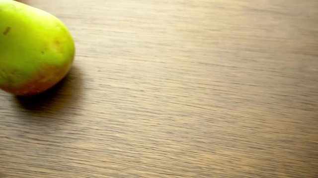 Panning overhead shot of fresh red and green pear fruits scattered on wooden tabletop