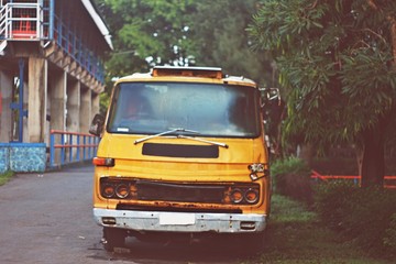Obraz premium front view of abandoned yellow old truck in the side street