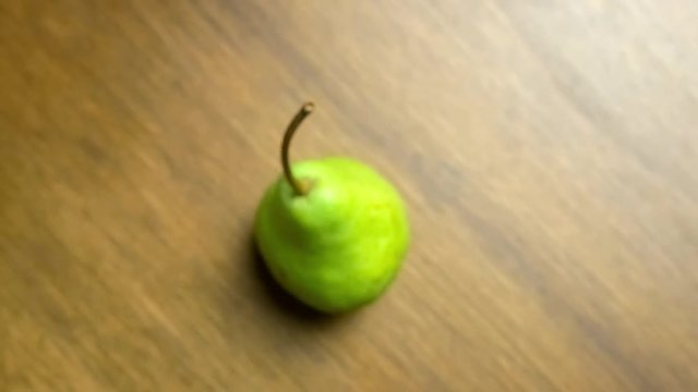 Green pear fruit closeup aerial panning out in a spiraling motion with copyspace
