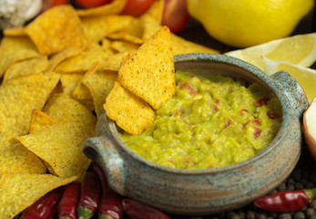 Guacamole in home crafted bowl with tortilla chips around.