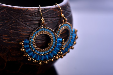Beaded earrings blue on a dark background. Beadwork.