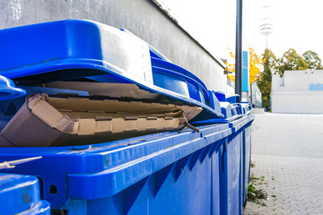 Fototapeta na wymiar Overflowing Paper Recycling Storage Bin Dumpster Row Multiple Ou