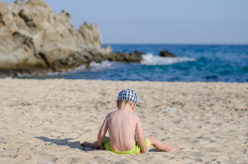 baby boy sitting on sand beach