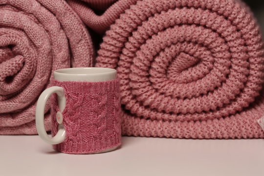 Two knitted pink blankets and cup. Close up