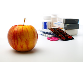 fresh ripe apple in front of pills, white background, shallow depth of field