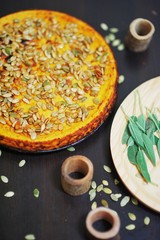 Spicy pumpkin pie with ricotta, topped with pumpkin seeds, top view.