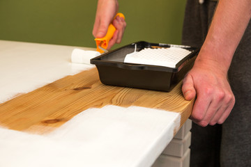 Ein Holztisch wird mit weißer Farbe lackiert
