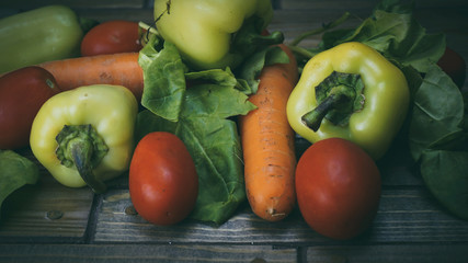 vegetables on a wooden background, carrots, peppers, tomatoes an