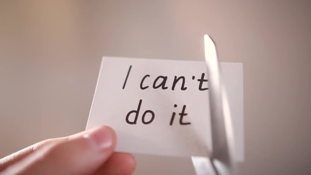 Man using scissors to remove the word can't to read I can do it concept for self belief, positive attitude and motivation