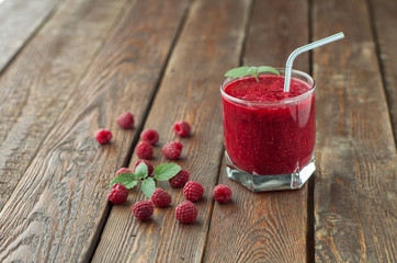 Raspberry smoothie with mint and straw in glass