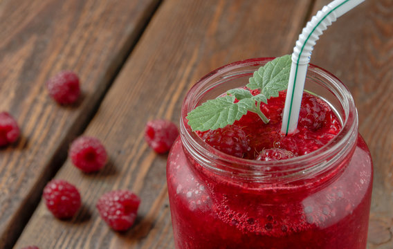 Raspberry smoothie with mint in glass jar with straw