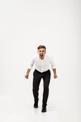 Young successful businessman in suit shouting over white background.