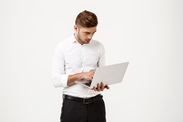 Young successful businessman typing on laptop over white background.