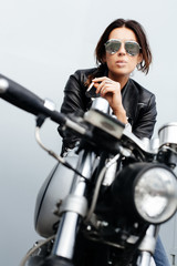 Fototapeta na wymiar Biker woman in leather jacket on motorcycle