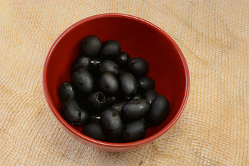 Canned pitted black olives in red bowl