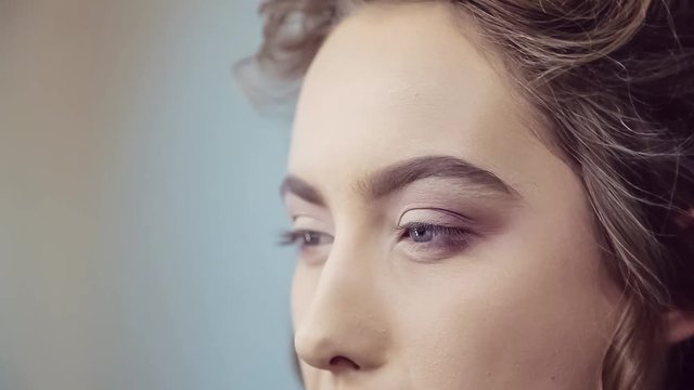 Make up artist doing professional eye makeup of young woman