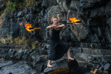 Girl in a black suit with flaming torches .