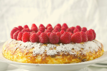 Cheesecake, souffle, cream mousse, pudding dessert with fresh raspberries and mint leaves on a white plate