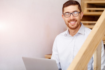 Portrait of young man sitting at the stairs in office