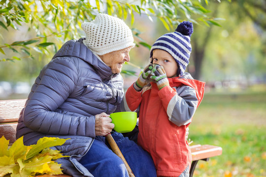 Senior woman and her great grandson drinking hot tea in autumn park