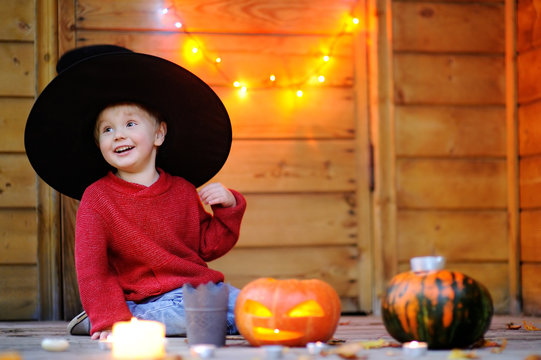 Cute little wizard playing with halloween pumpkins