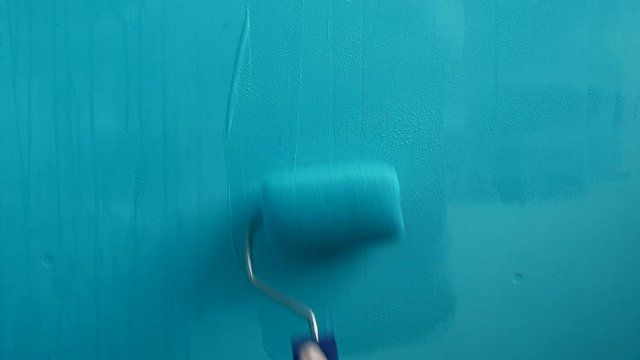 woman paints the wall work roller blue, artist painter for repair art