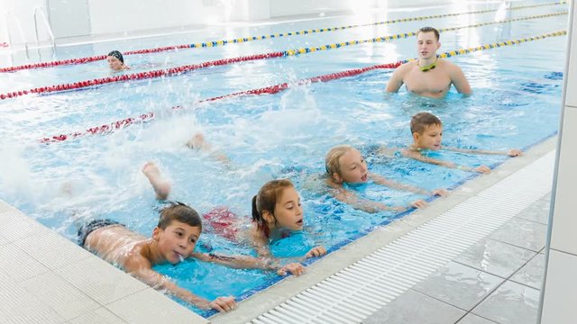 Instructor or coach and group of children doing exercises in swimming pool