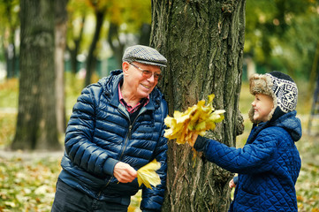 Grandfather walking with grandson playing in autumn Park