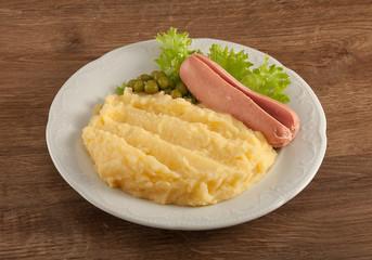 Mashed potatoes with green lettuce, peas and small sausage