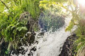 River is flowing down through hill. Grass growing in the hill.