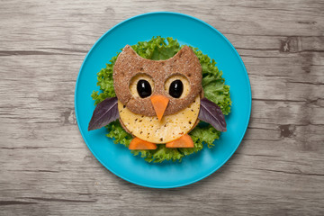 Owl made of bread and cheese on plate and board