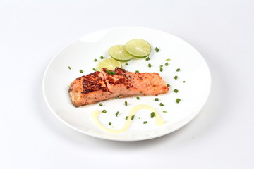 Grilled salmon topped minced shallot ,mayonnaise and sliced lemon on white dish. Isolated.