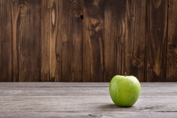 Green apple on wooden table close up