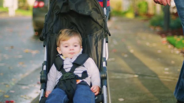 Adorable baby boy being pushed in a stroller, on a walk with his parents