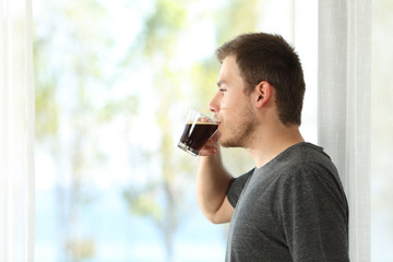 Man drinking coffee looking through window