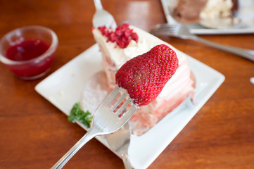 Strawberry on a fork,Crepe cake with strawberry sauce on table.selective focus