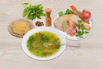 Chicken soup in white dish and ingredients for its cooking
