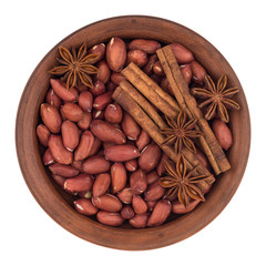 peanuts with star anise and cinnamon sticks in a ceramic bowl.
