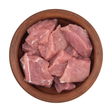 Raw meat is cut into pieces in a brown plate.