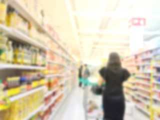 Blurred woman standing selected products with a trolley at a supermarket