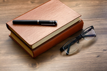 books, glasses and pen on the table.