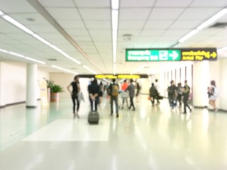 Fototapeta na wymiar Traveler walking the airport terminal hall and a handbag behind her. Blured background.