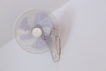 electric fan hanging on white wall