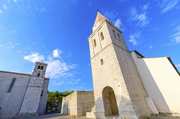Fototapeta na wymiar Pyramidal tower of the Church of our Lady of Health, a romanesque cathedral formely named St Michael the archangel, basilica at the Square of the Glagolitic housed monasteries on Krk island, Croatia.
