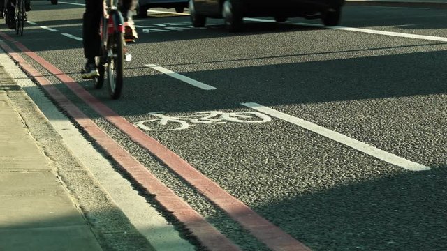 Traffic on the Road of the Blackfriars Bridge, London.Cyclists and cars passing on the Concrete, Bicycle lane and signs are visible.
Long shadows, sunset.